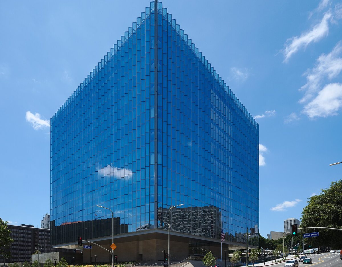 The glass-clad United States Courthouse at First Street and Broadway in downtown Los Angeles, seen from street level under a clear sky.