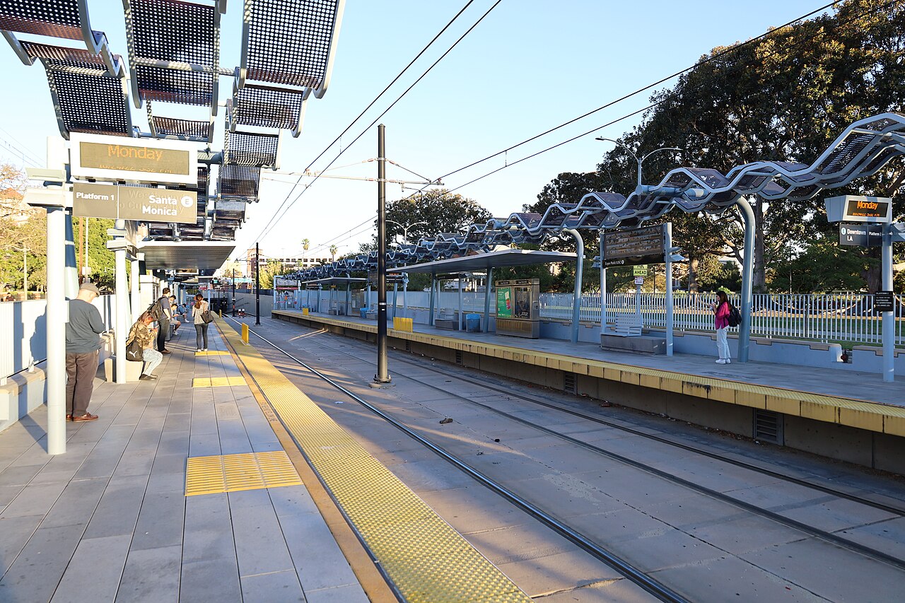Riders waiting on both platforms at the Expo Park/USC Metro station, with signs overhead reading Santa Monica and Downtown LA