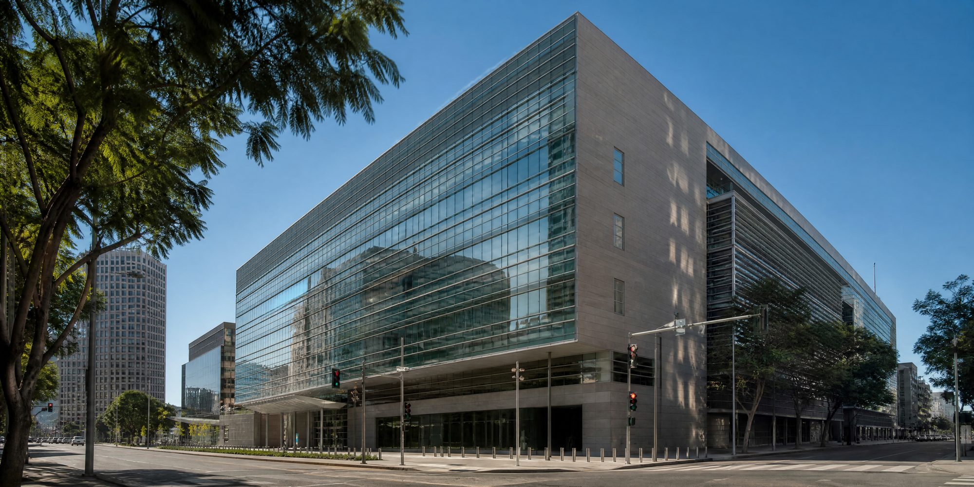 The glass-clad United States Courthouse at First Street and Broadway in downtown Los Angeles, seen from street level under a clear sky.