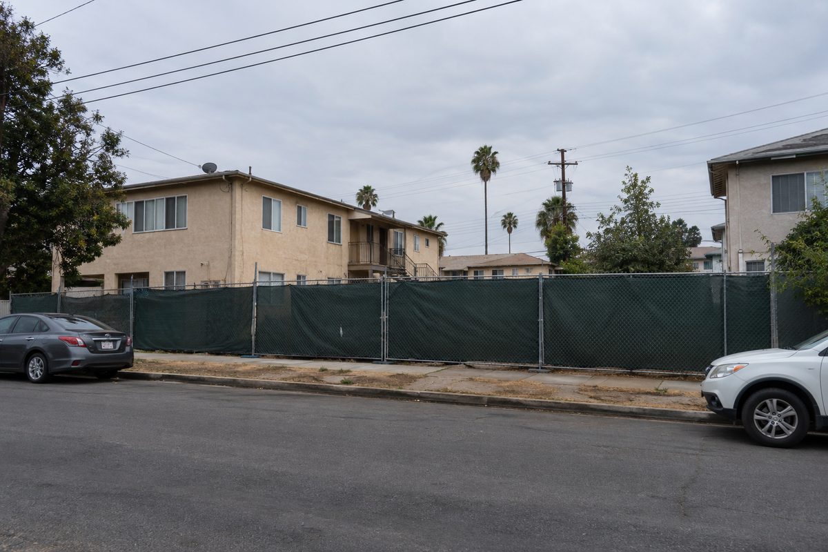 Chain-link construction fence along a North Hollywood side street near Lankershim Boulevard on an overcast afternoon, low apartment buildings behind it.