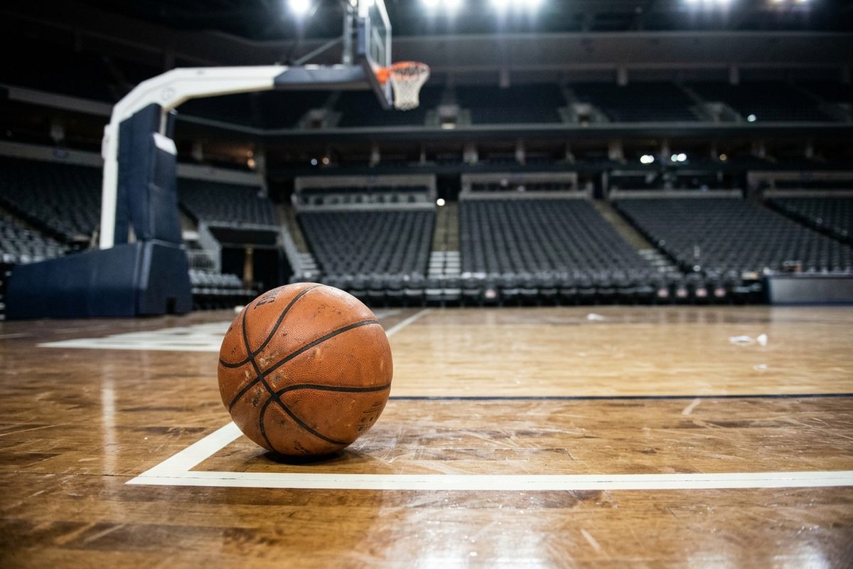 An orange NBA basketball resting on the hardwood near the baseline of the Target Center court in Minneapolis under the arena lights at night.