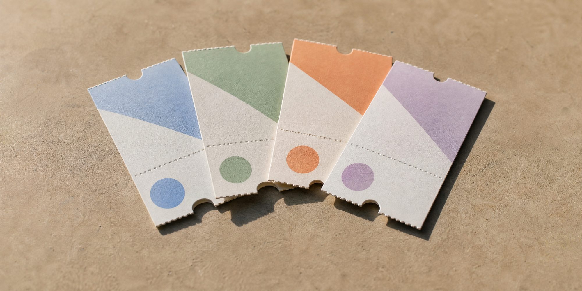 Photo illustration: four paper timed-entry tickets fanned in a row on a plain surface, each printed with a different date and no legible venue name — overhead flat-lay, hard noon light, no text, no logos, no recognisable building