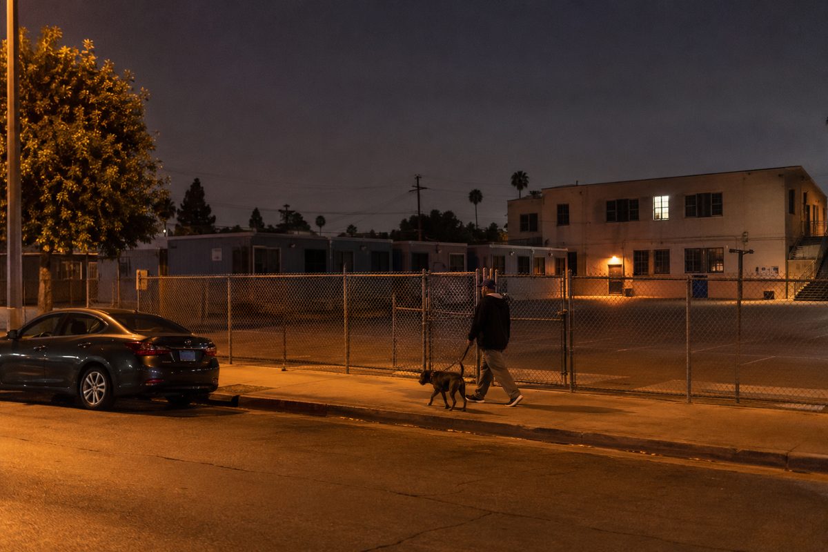 A Los Angeles public school campus at night under orange streetlights, with rows of dark classroom bungalows behind a chain-link fence.