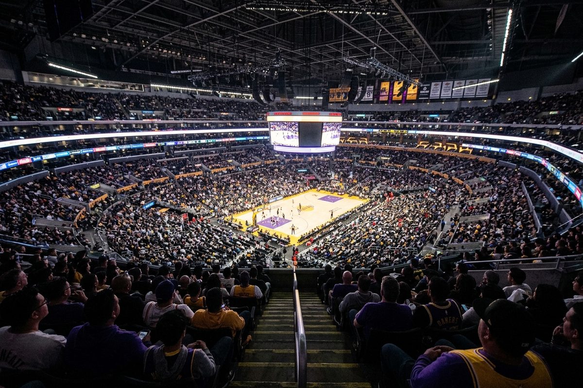 Photo illustration of the seating bowl at Crypto.com Arena during a night basketball game, with fans in purple and gold around a lit hardwood court.