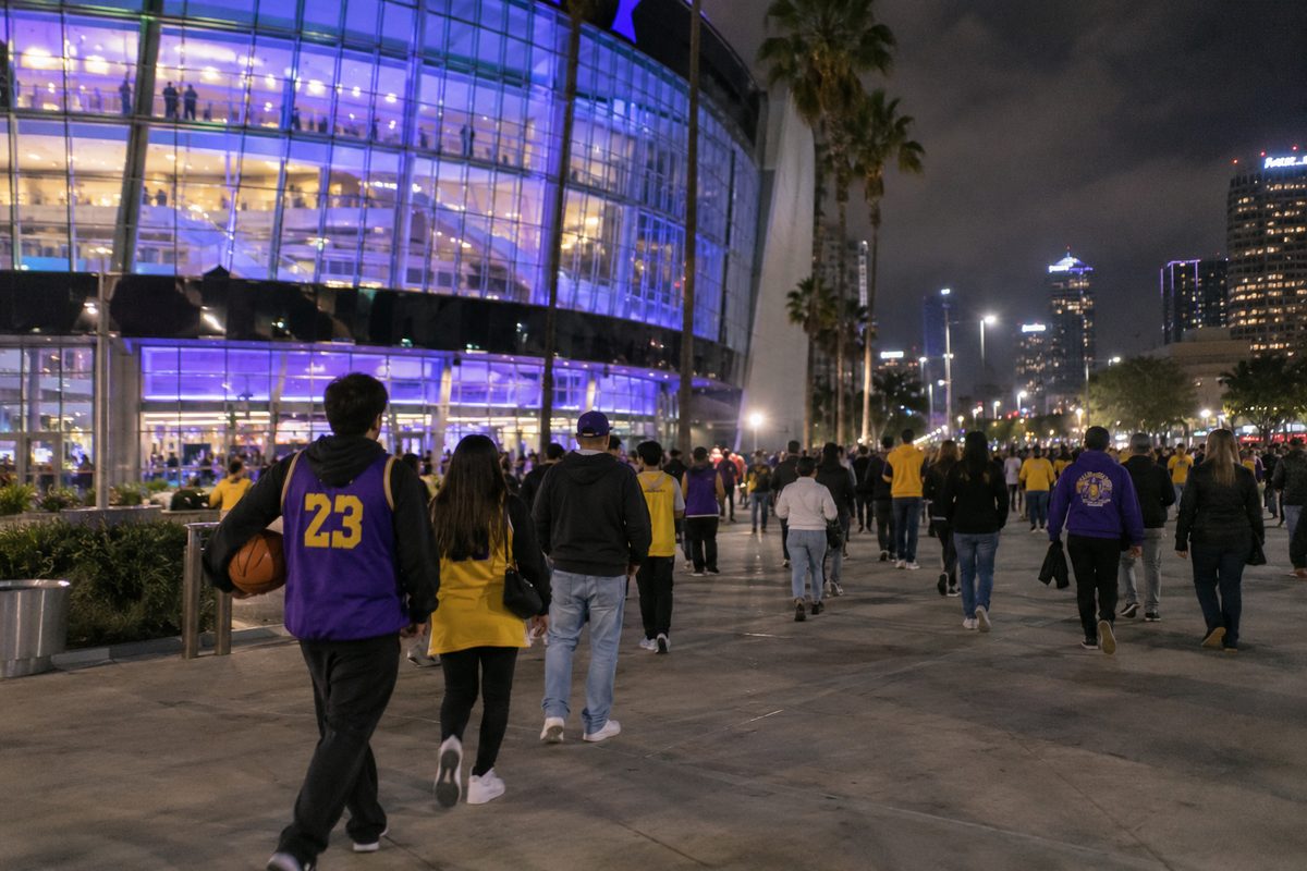 Fans in purple and gold walking out of Crypto.com Arena at night after the Lakers' loss to the Portland Trail Blazers