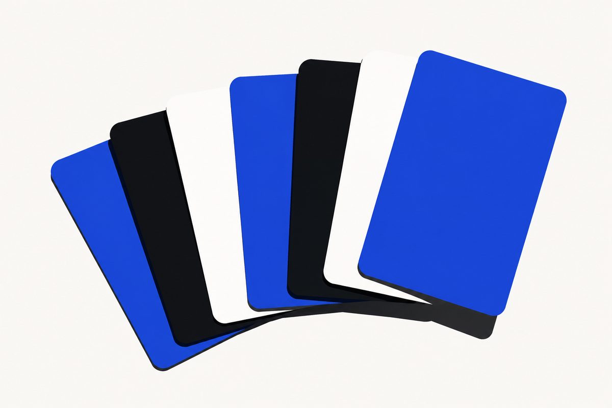 Illustration: Editorial illustration: seven blank membership cards fanned in a graphic overhead row on a plain pale surface, each a different flat color, one card lifted slightly clear of the others. Crisp, graphic, hard noon light; no text in the image, no logos, no readable numbers, no brand marks.
