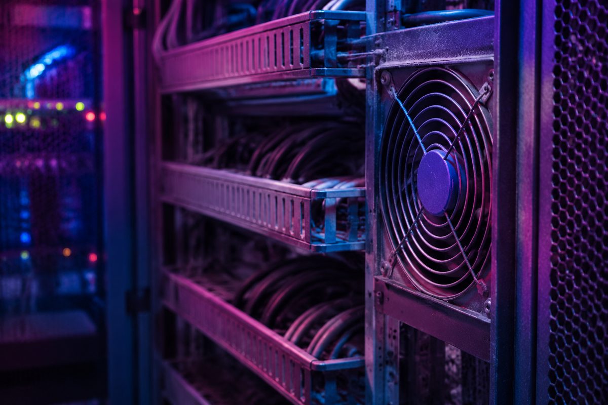 Extreme close-up of stacked network cable trays and a cooling fan grille in a dim server corridor, lit by colored indicator light.
