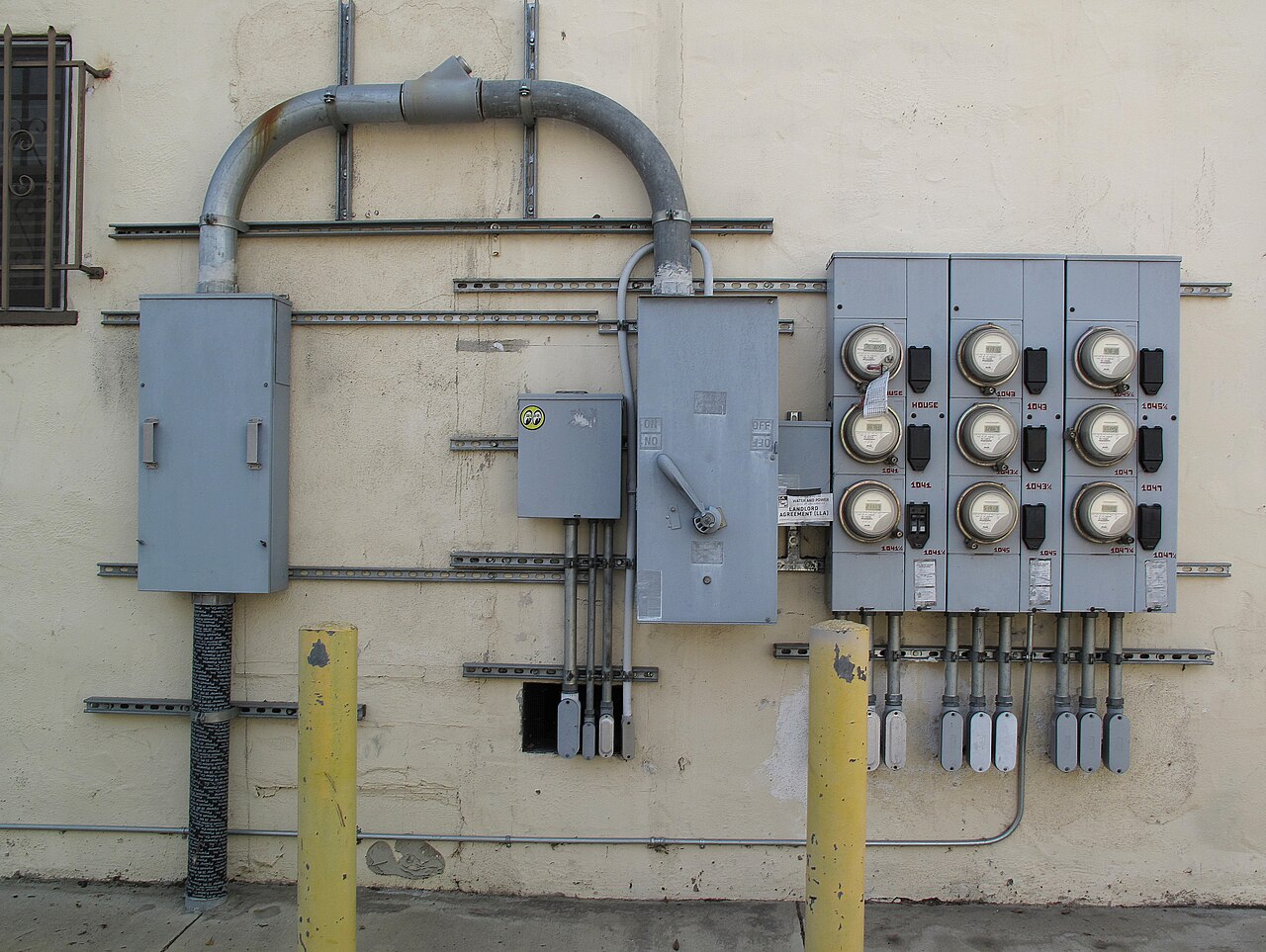A bank of electricity meters mounted on the stucco back wall of a multi-unit apartment building in Los Angeles