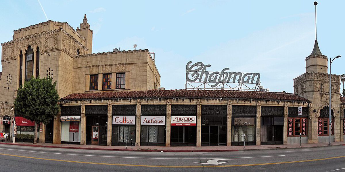 The Chapman Park Market Building on West Sixth Street in the Mid-Wilshire district, a low tile-roofed block with an arcaded row of storefronts and an empty street in front