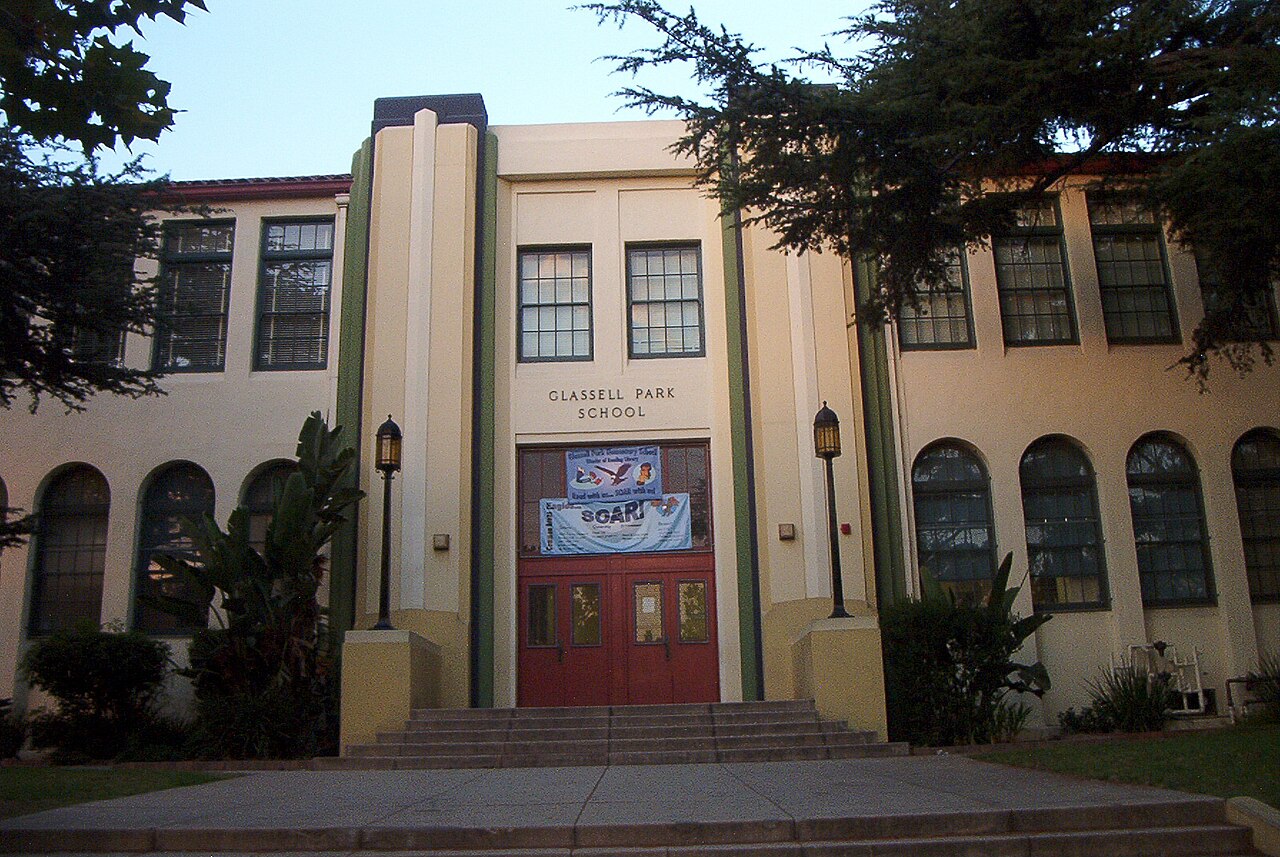 The cream stucco facade of Glassell Park School in Los Angeles, with arched ground-floor windows, red double doors and carved lettering above the entrance