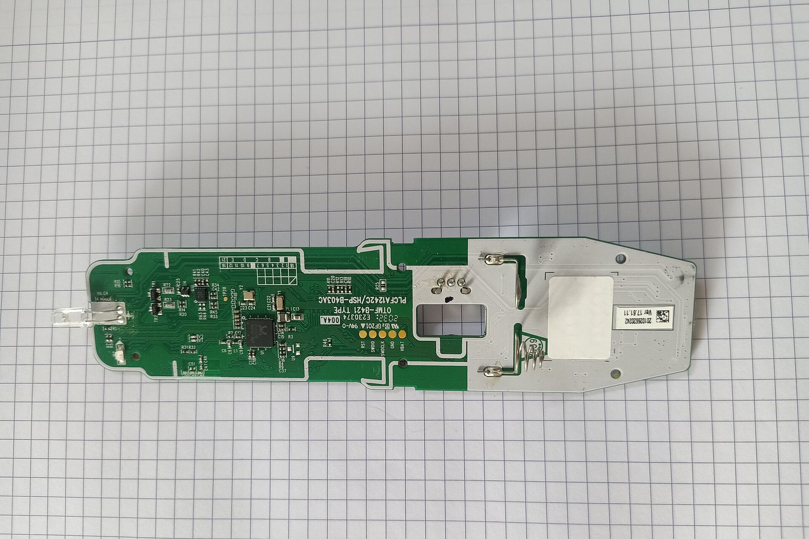 A green circuit board with chips and a small antenna, taken out of an LG smart TV, lying on graph paper.