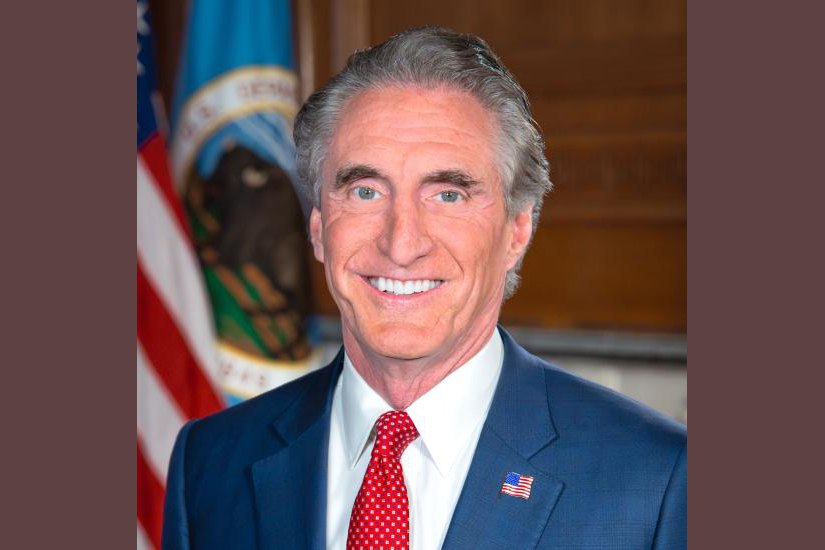 Official portrait of Interior Secretary Doug Burgum in a suit against a plain background.